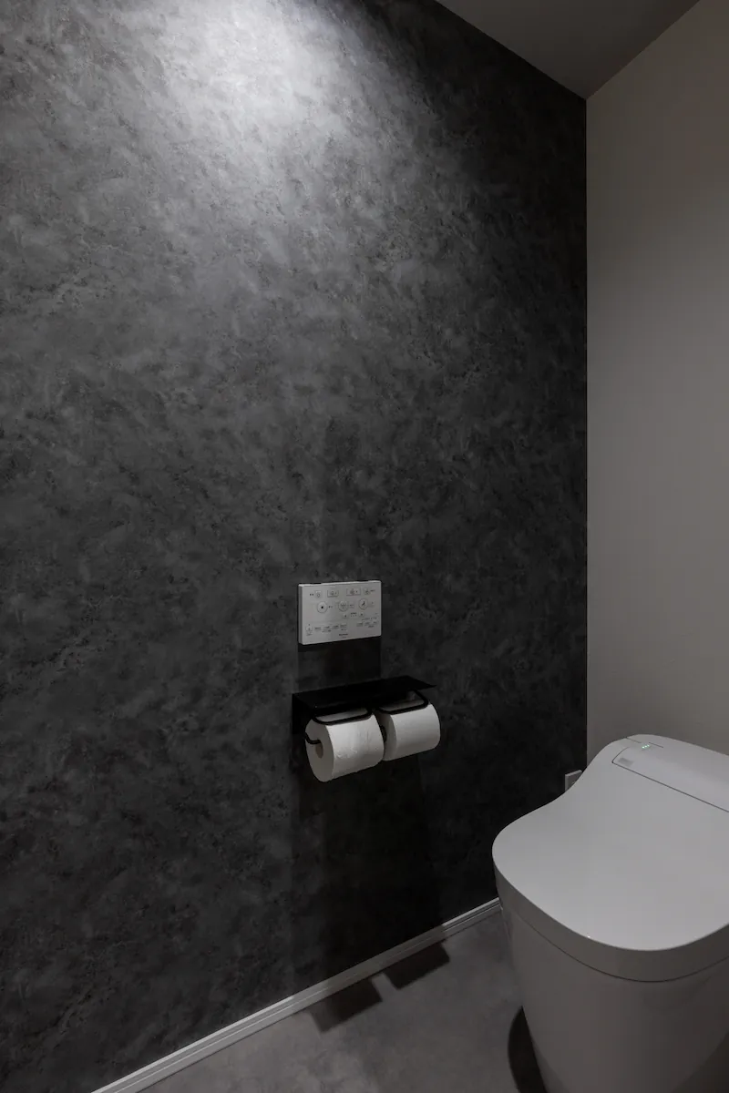 ダークグレーのテクスチャ壁紙とタンクレストイレのトイレ空間